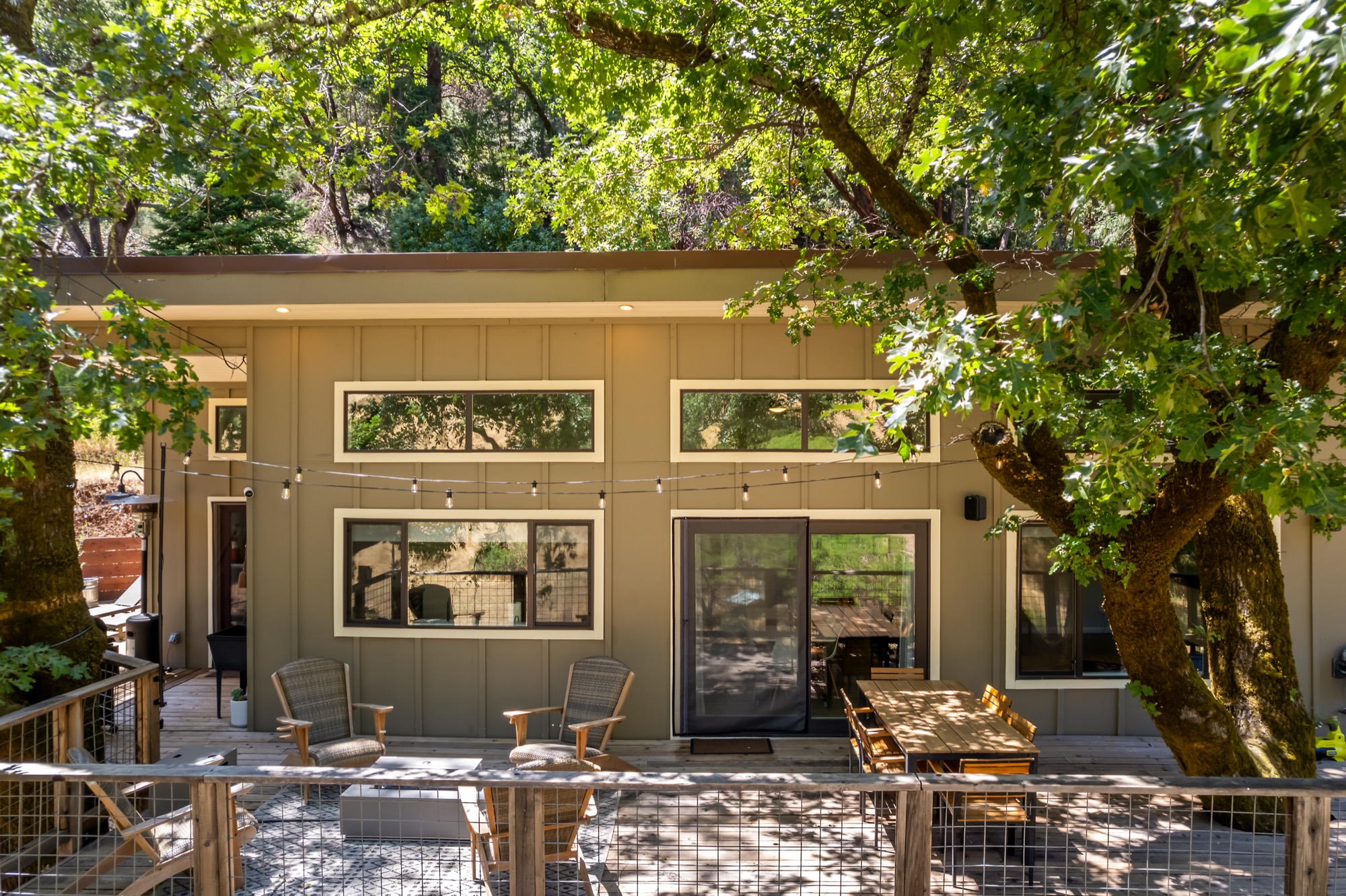 Modern farmhouse exterior nestled under oak trees